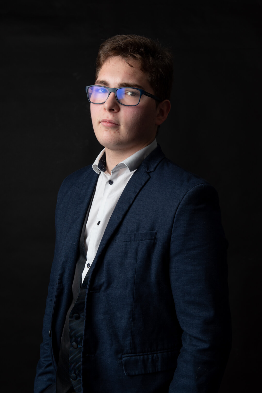 portrait sur fond noir d'un jeune homme avec reflets dans ses lunettes