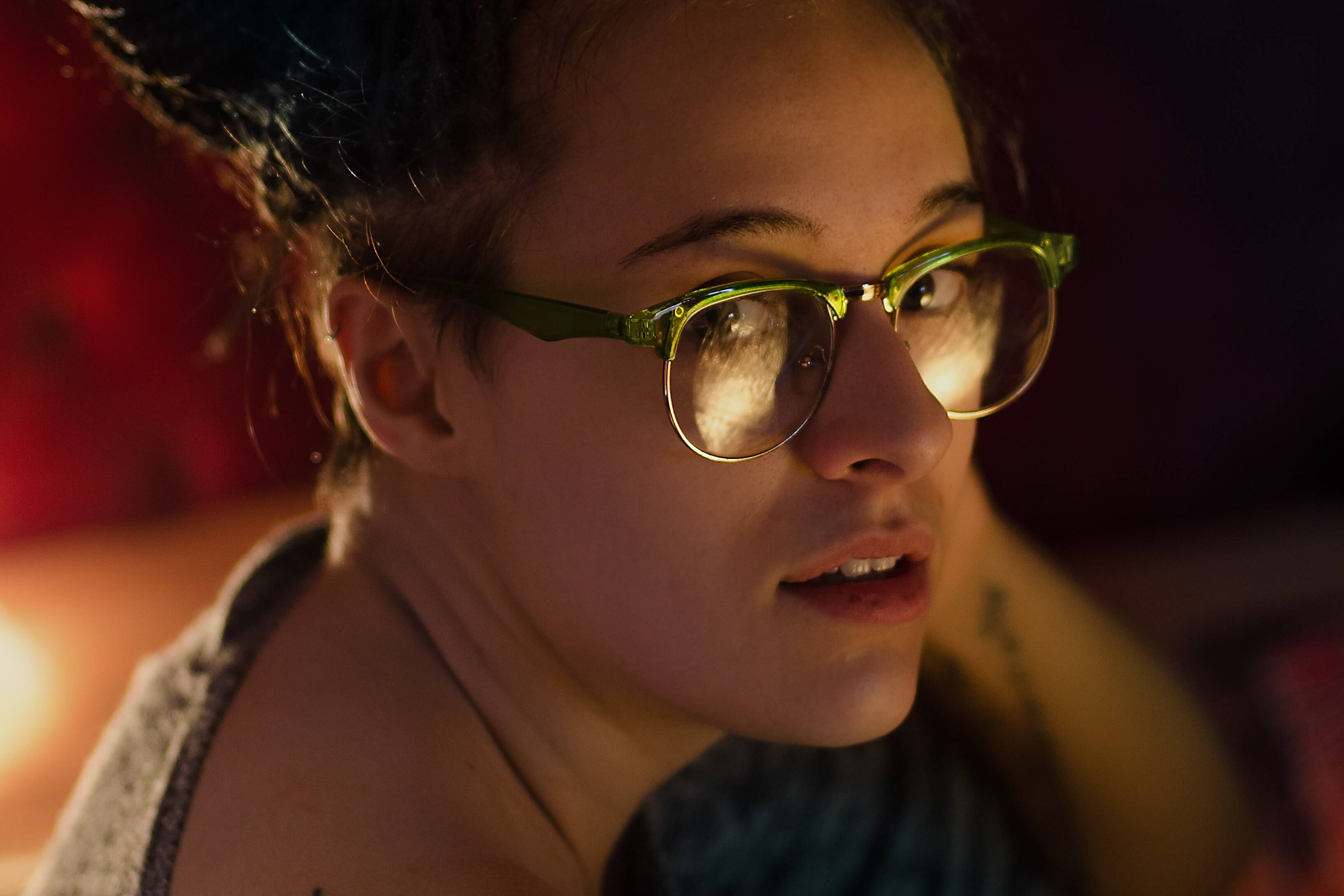 femme avec des lunettes remplies de reflets dans un éclairage tamisé