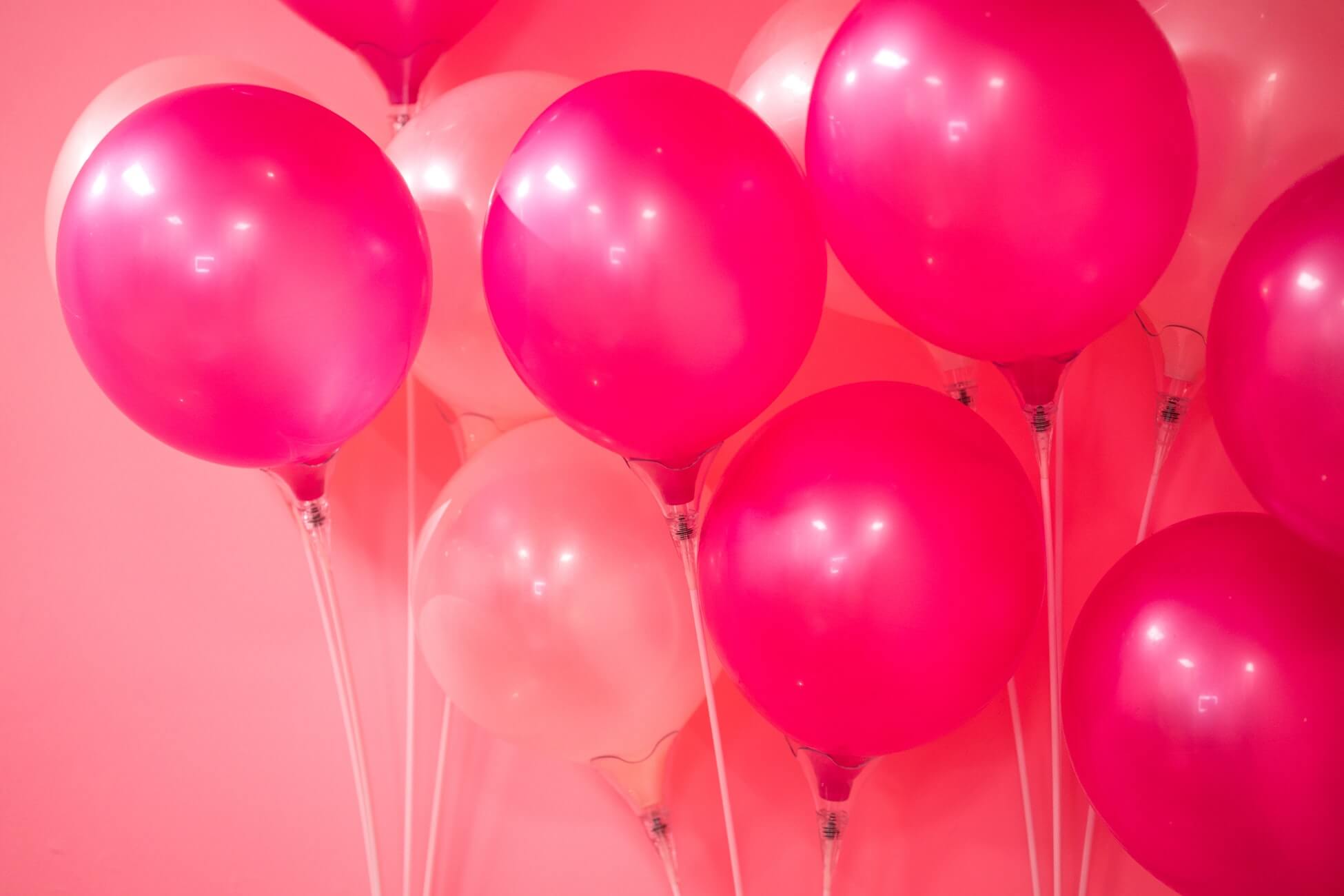 ballons roses foncés et rose pâle à saturation intense sur fond rose gomme